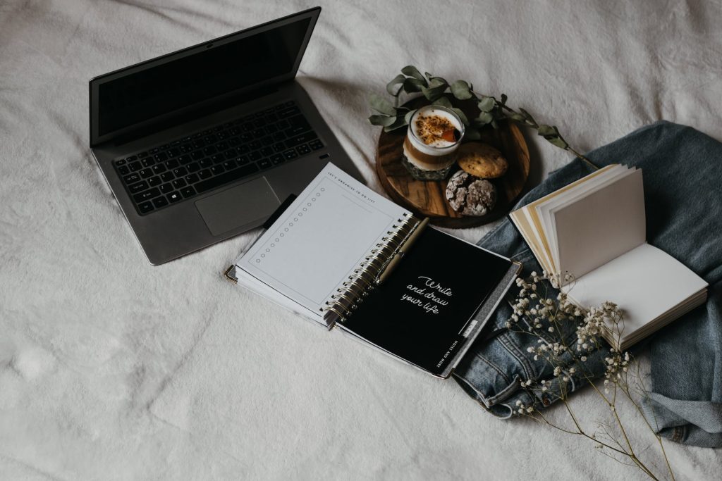 black and white book beside black and silver laptop computer