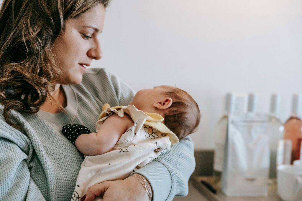 Maman avec un bébé dans les bras qui peut profiter et se sentir bien grâce à tous les indispensables en post-partum auxquels elle a pensé en amont
