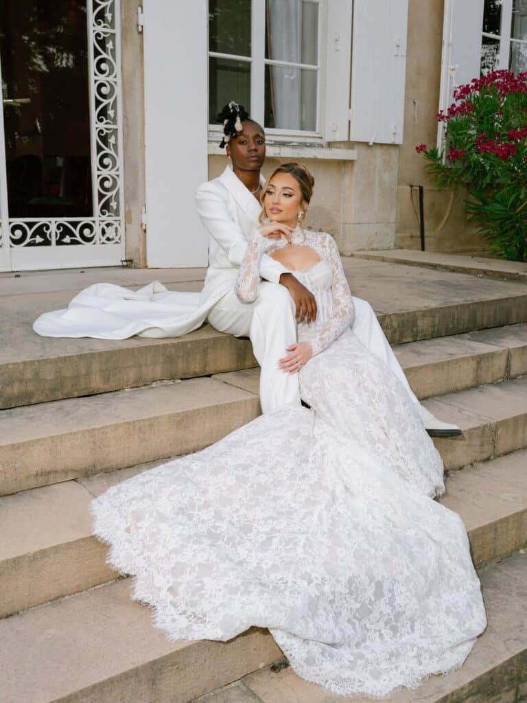 Photo du couple Melvine Malard et Justine qui posent sur les marches de leur lieu de réception de mariage