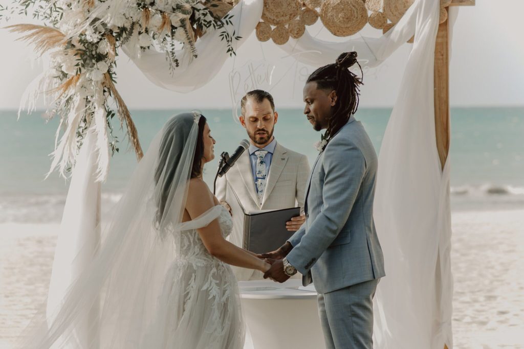 mariés sur la plage lors de leur cérémonie laïque en train d'échanger leurs voeux de mariage