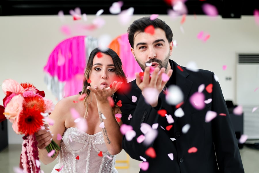 couple de mariés très rock'n'roll qui soufflent sur des confettis colorés