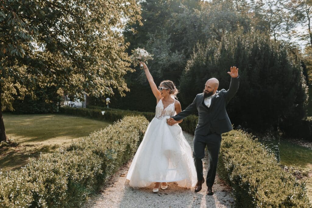 photo de mariés heureux qui partent faire leur photo de couple le jour de leur mariage